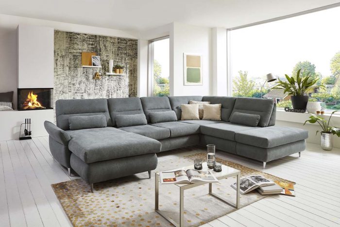 Sofa in U-Form in grauem Stoff mit Kimme im Rücken und Nierenkissen