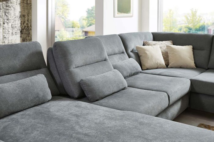 Sofa in U-Form in grauem Stoff mit Kimme im Rücken und Nierenkissen und Sitztiefenverstellung