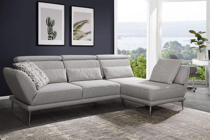 Hellgraues 2-Sitzer-Sofa mit Longchair und klappbarem Kopfteil. Die Winkelfüße sind chromfarbig.