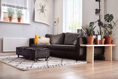 Dunkelgraues Stoffsofa mit Kissen, dunklem Couchtisch und hellem Teppich