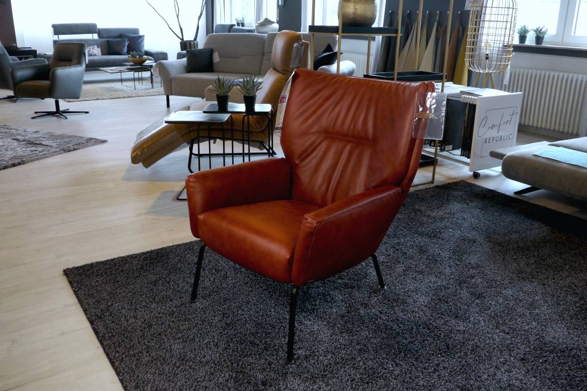 Roter Ledersessel mit schwarzen Metallfüßen und Einzug im Rücken